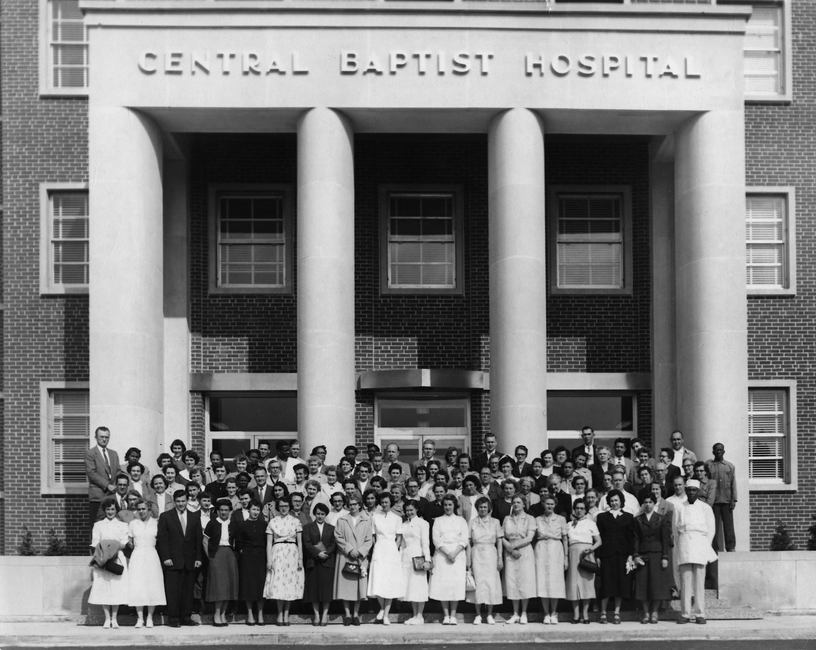 Black and white photo  of group of people outside of a hospital