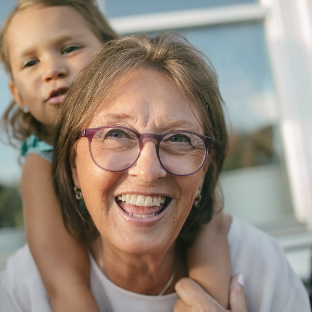 Mature grey haired woman smiling with look of enjoyment and confidence on her face.