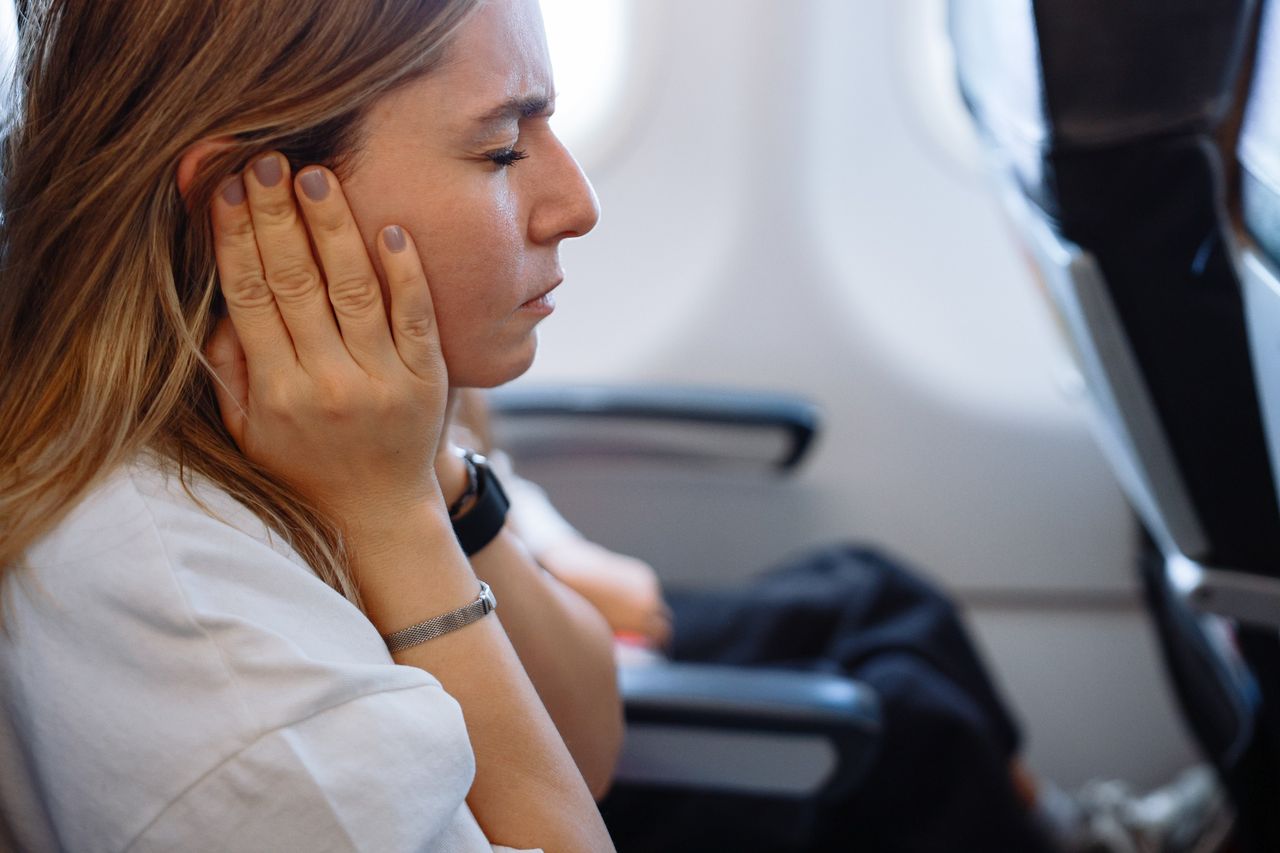 Woman on plane holding her ears