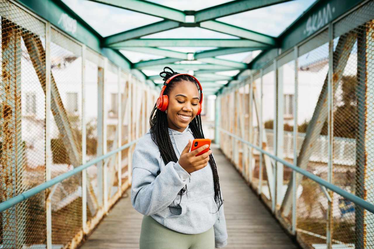 Smiling woman listening to music on her phone with red headphones