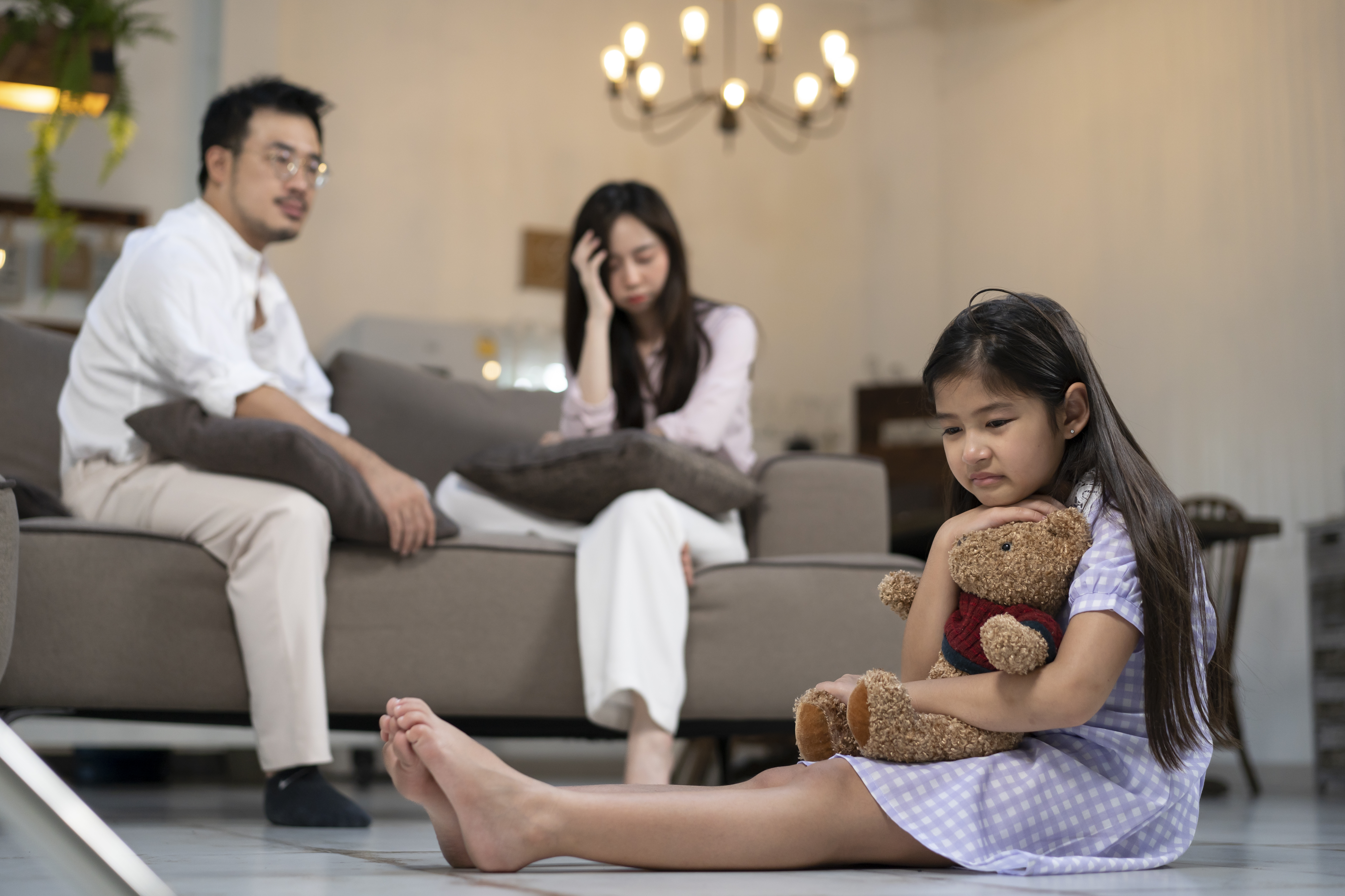 Parents Sitting on Couch Looking at Child on the Floor