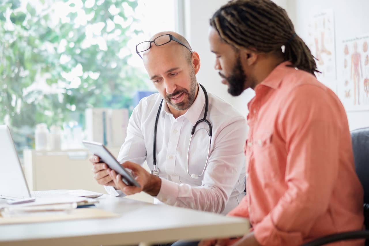 Doctor showing a smart tablet to a man