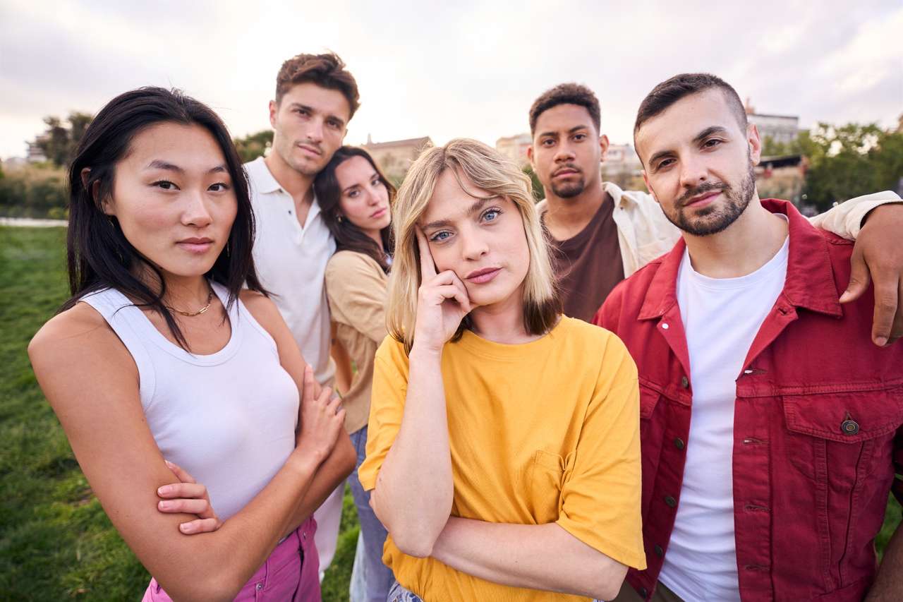 Group of five young adults standing outdoors in a park