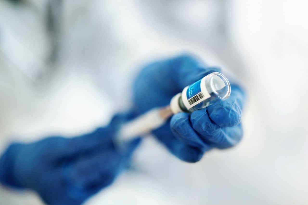 Gloved healthcare worker with needle and vial of medicine