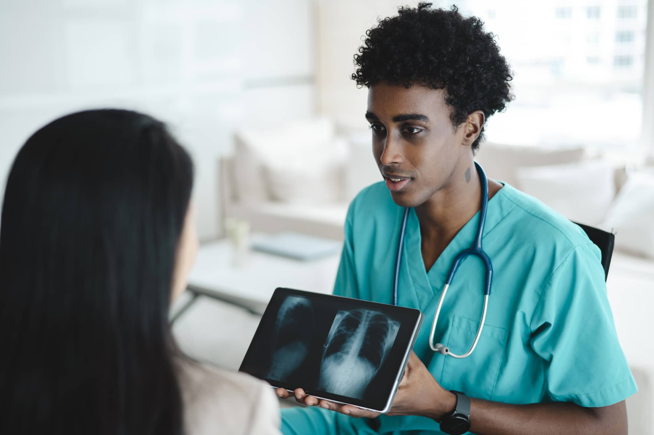 Man showing an xray on a tablet to a patient