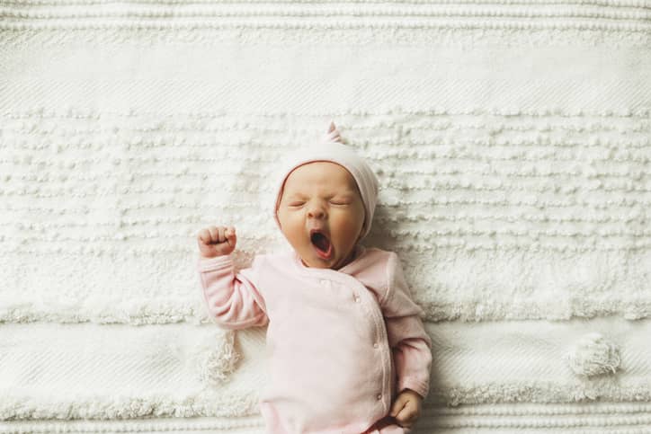 Baby Yawning While Lying On A Blanket