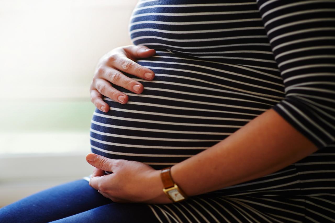 Hands cradling striped pregnant belly
