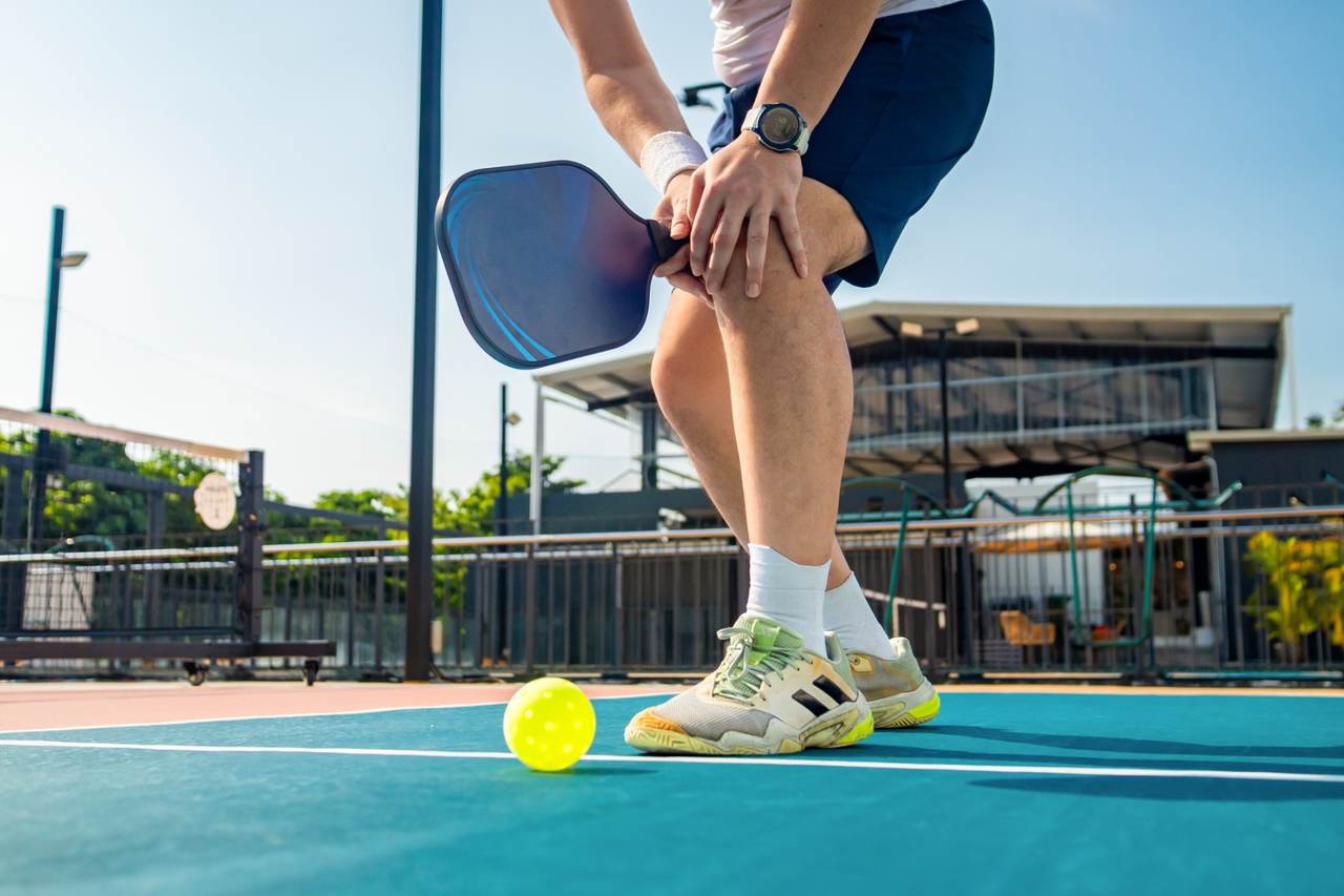 Man playing pickleball with hurt knee