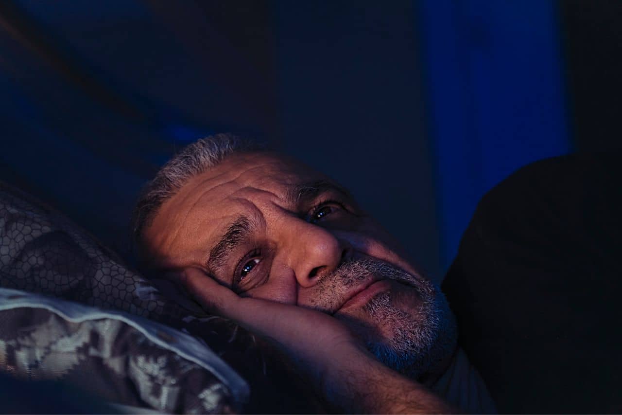 Man laying in bed awake