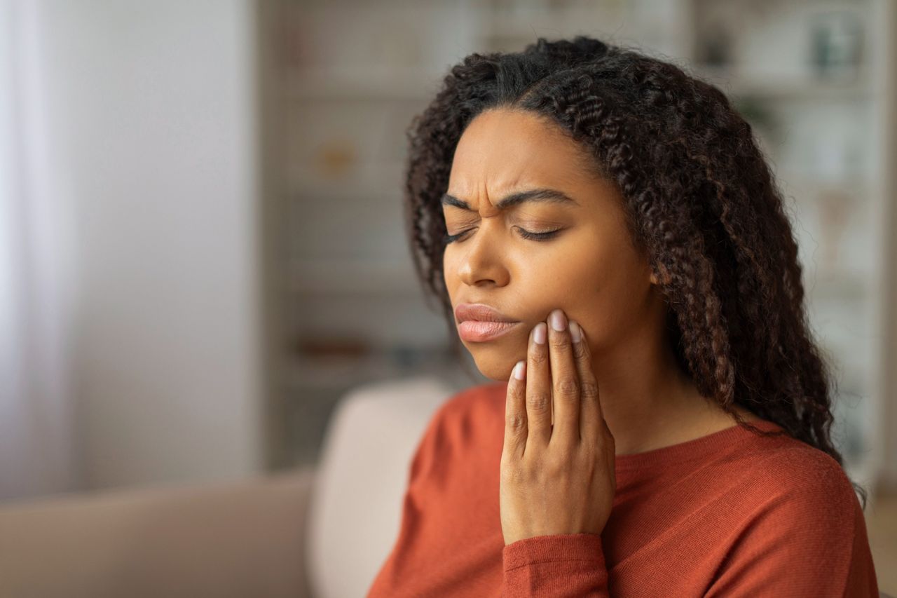 Woman holding cheek in pain from toothache