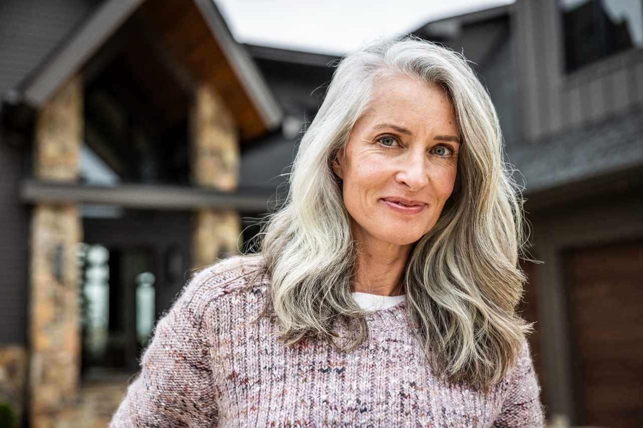Smiling woman standing outside a modern house.