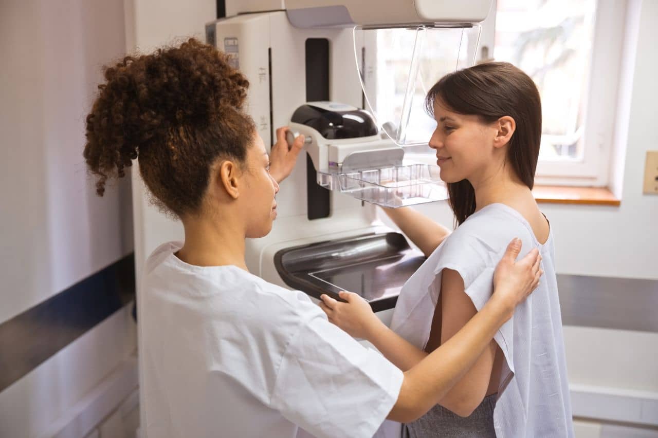 Woman and medical staff person by mammogram machine