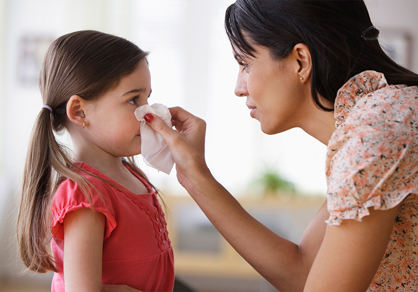 Mother with tissue wiping a girl's nose