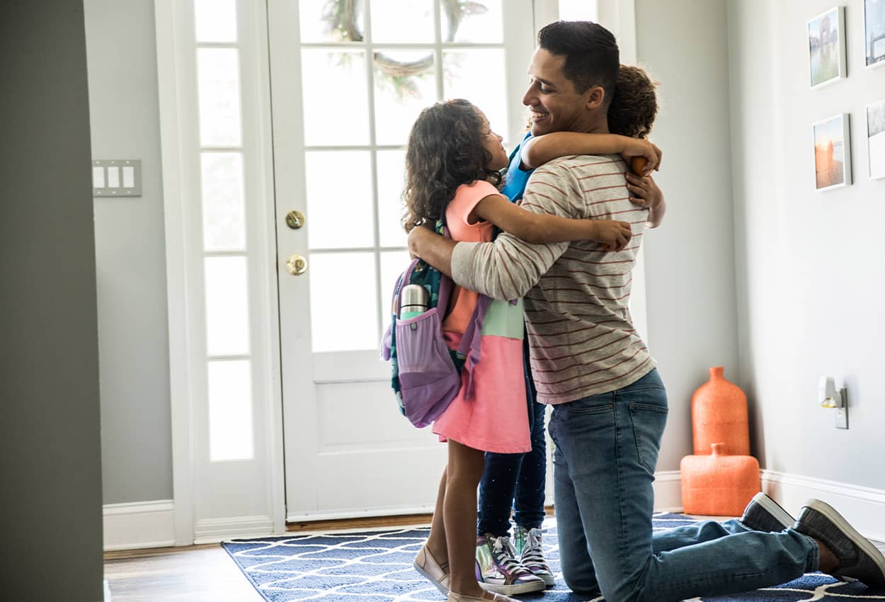 Dad hugging his kids as they go to school
