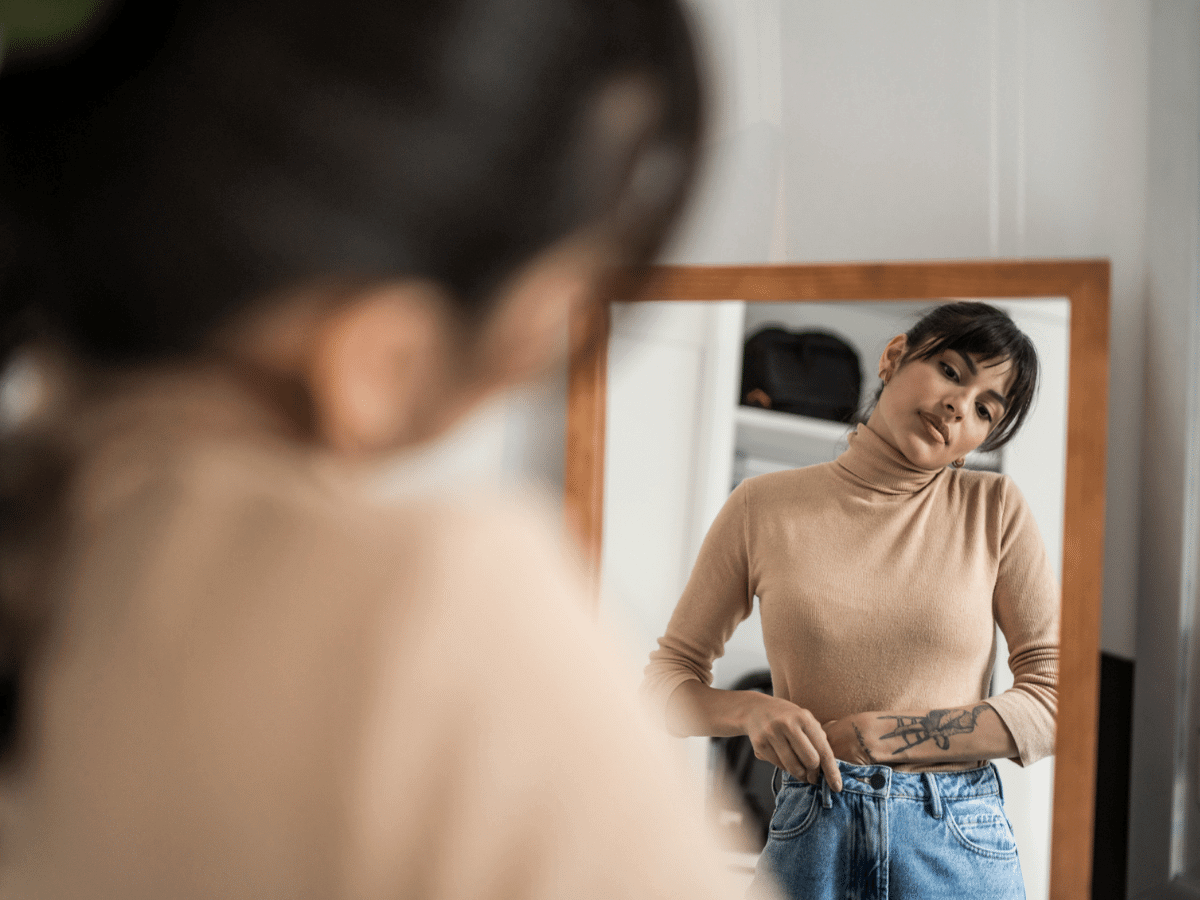 Woman getting dressed and looking in a mirror