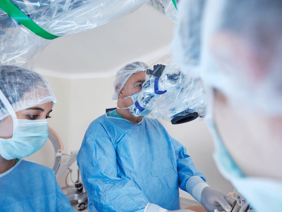 Surgeon wearing protective equipment uses a robotic surgery device in an operating room