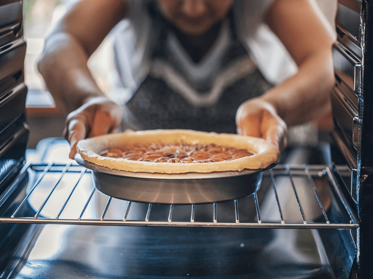 Woman putting a pecan pie in the oven for the holidays
