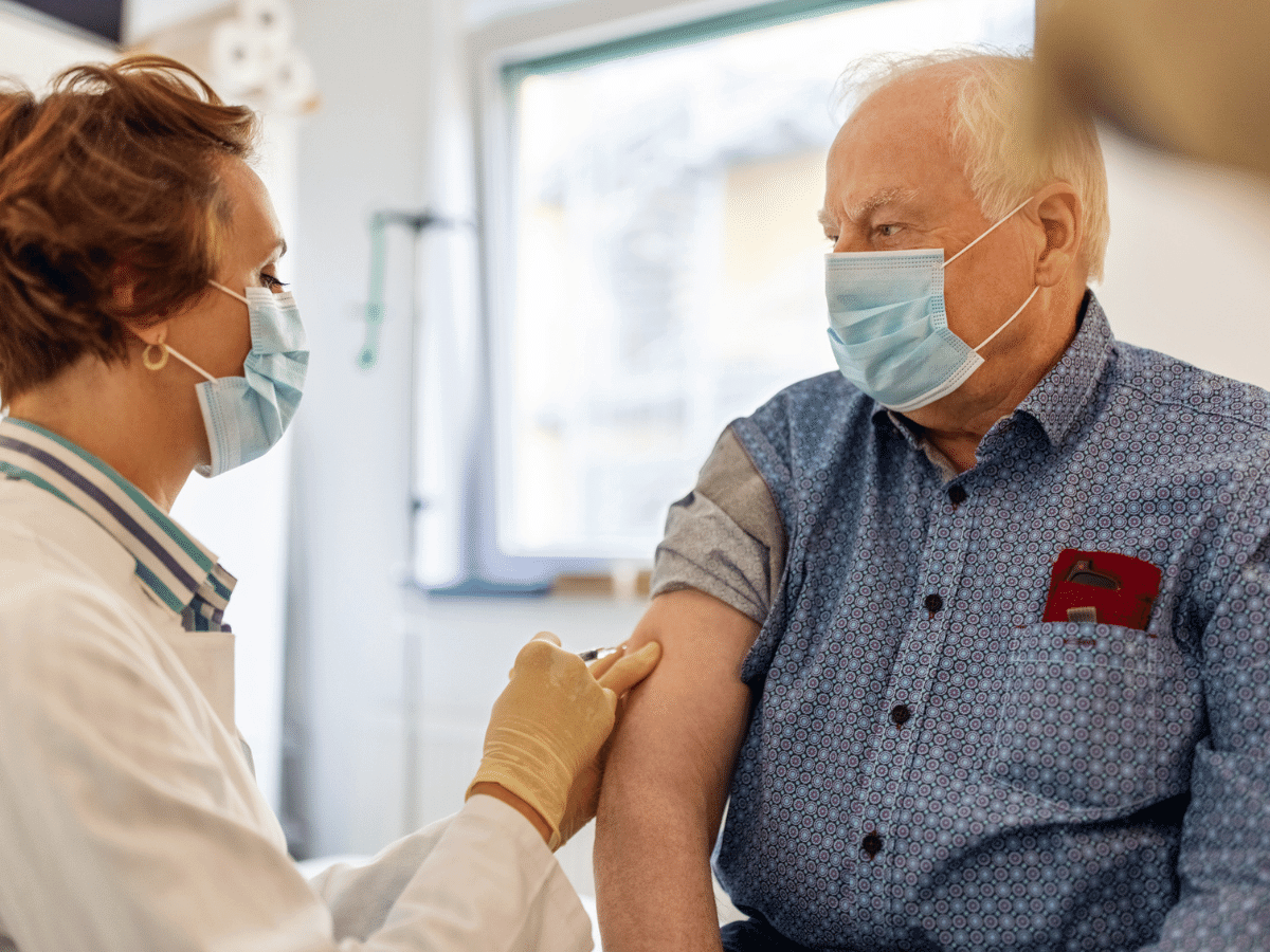 Older man receiving a COVID-19 vaccine in his doctor's office.