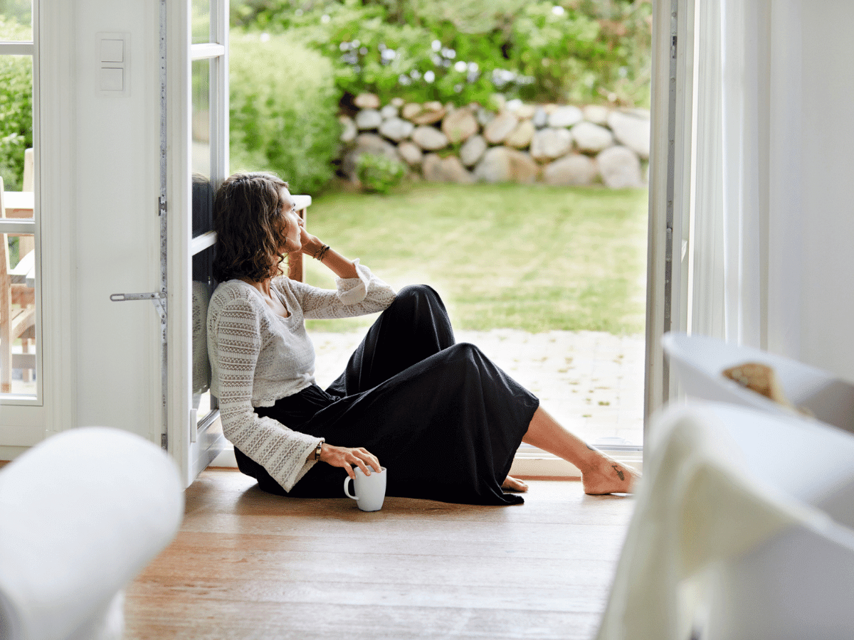 Woman sitting on the floor inside her house looking outside