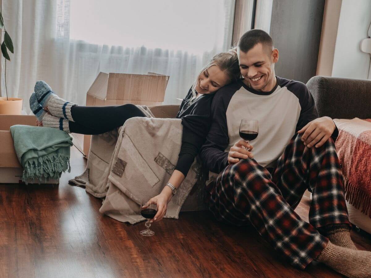 Couple at home sharing a glass of wine and laughing.