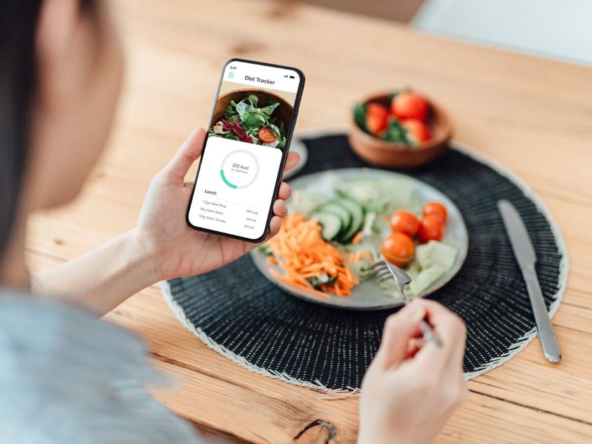 Close up of woman's plate of healthy food and smartphone showing her tracking her macros