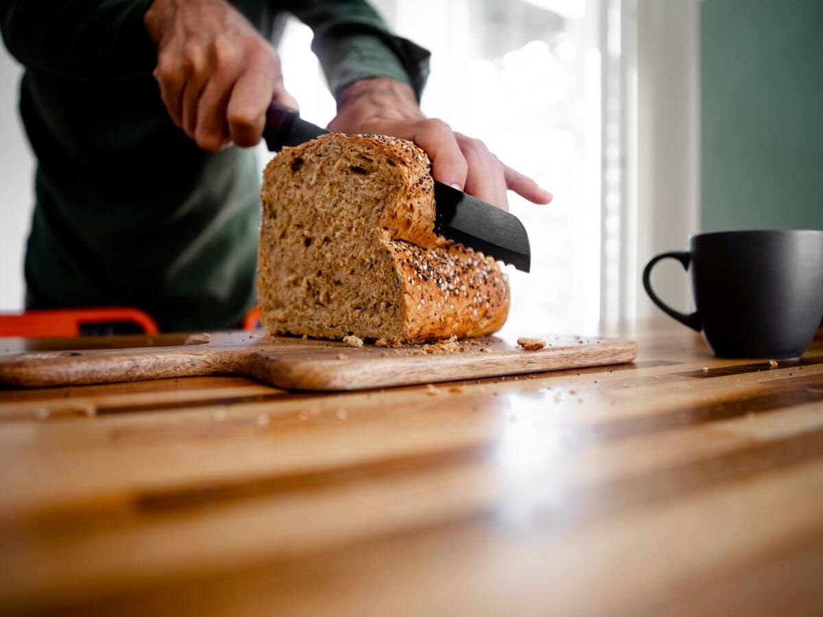 close up photo of a man slicing a loaf of bread