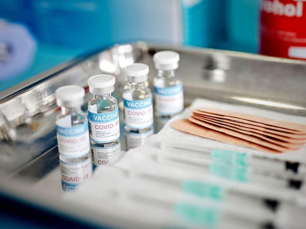 Close up of a medical tray holding vials of COVID-19 vaccine, syringes, and bandages.
