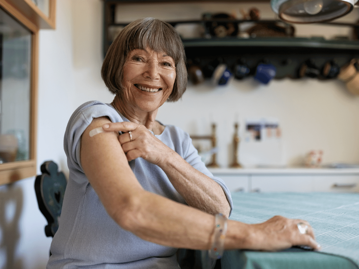 Woman showing bandaid on upper arm from receiving a vaccination