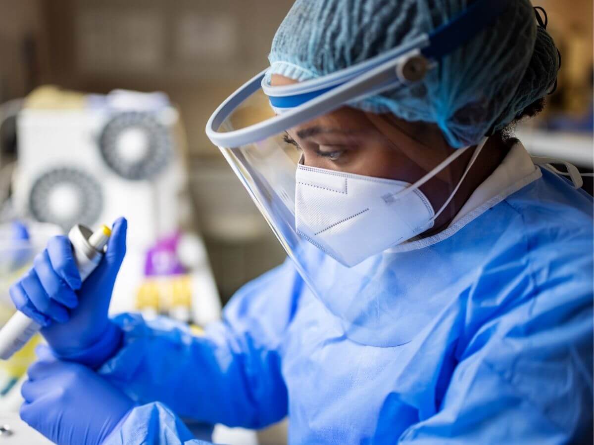 Female medical researcher in protective equipment works in a lab