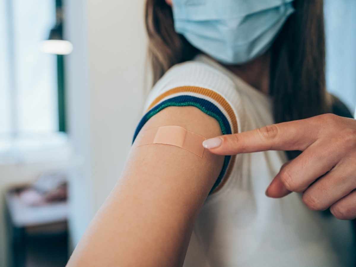 Close up of a young woman's arm showing bandaid from vaccination