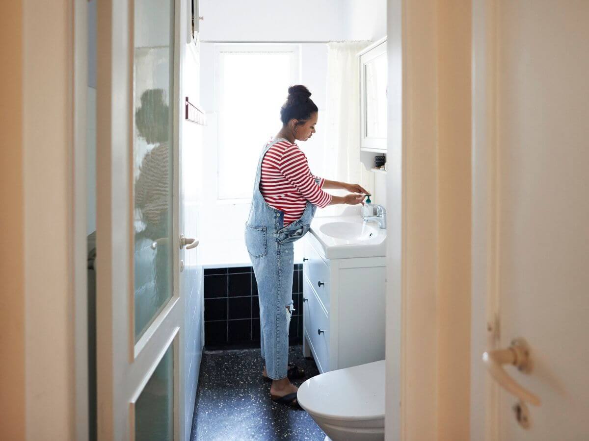 Pregnant woman washing her hands in the bathroom