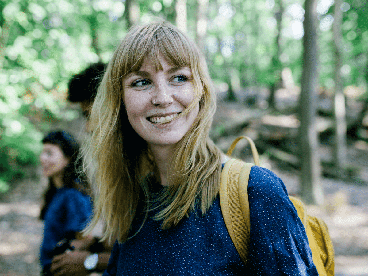 A young woman smiling while on a walk outside with friends.
