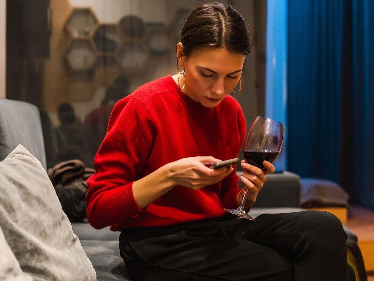 Young woman drinking a glass of red wine at home in the evening