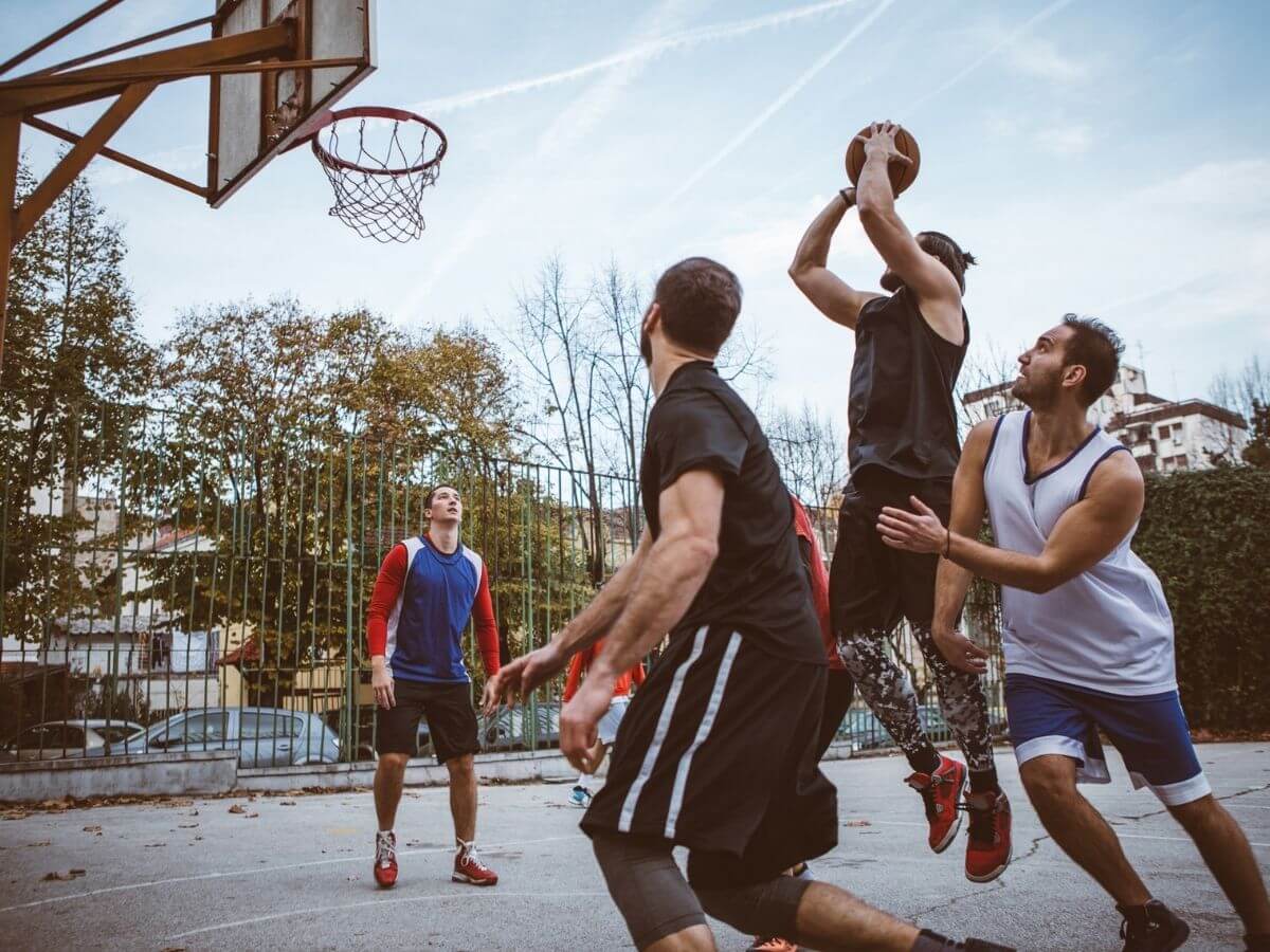 Group of men play basketball on an outdoor court