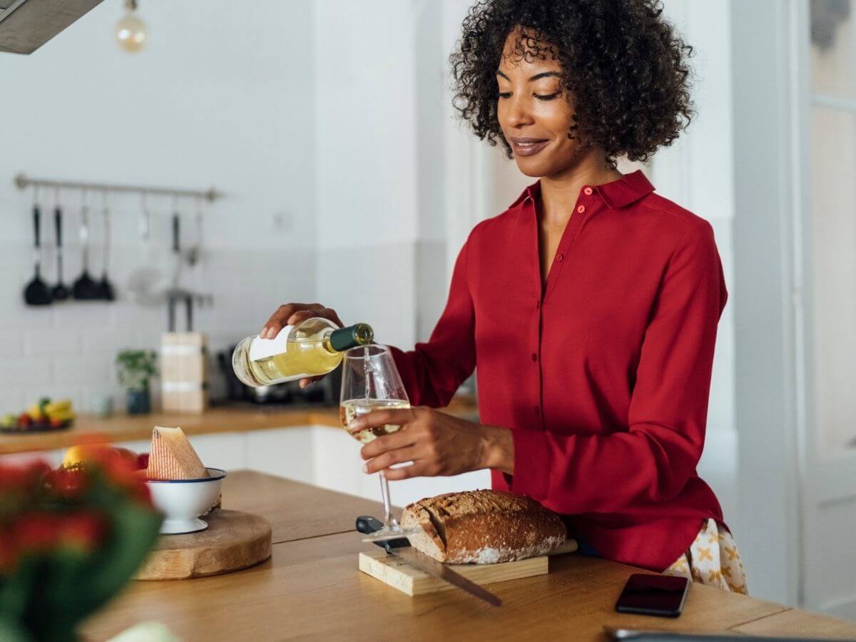 Woman pouring a glass of wine in the kitchen