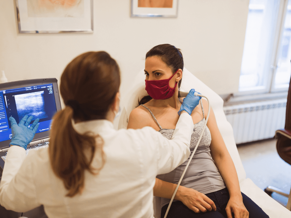 Female doctor using an ultrasound machine on a female patient's neck.