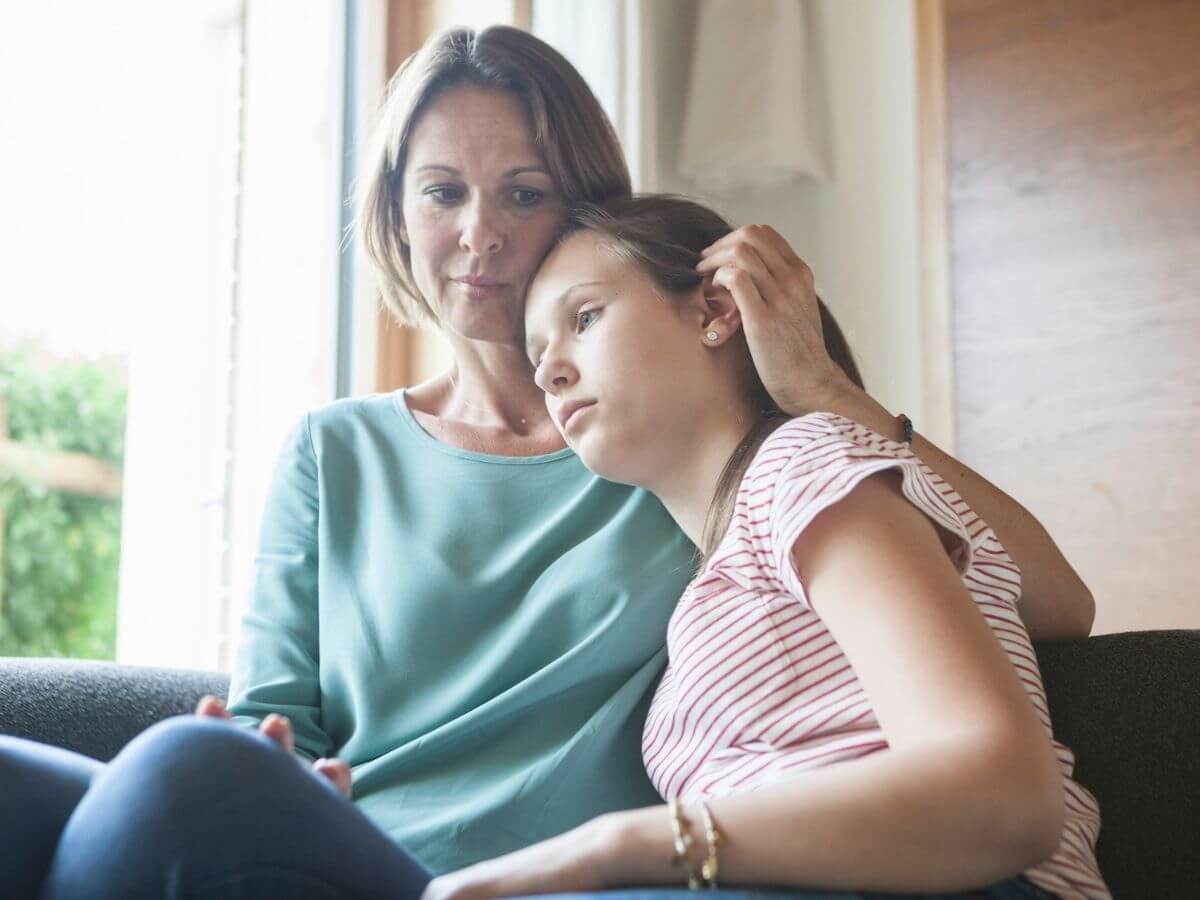 Mother consoling her daughter on the couch