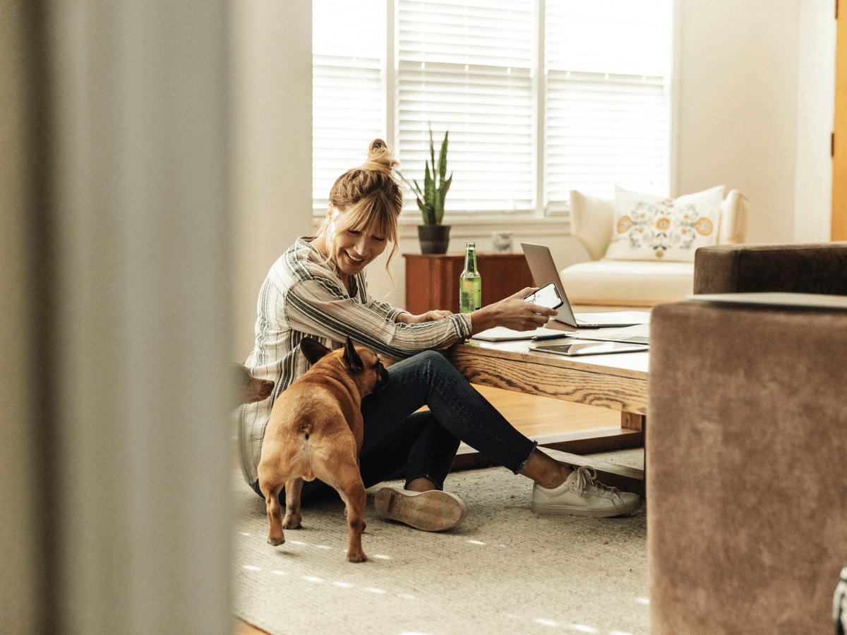 Woman sitting on the floor at home playing with her dog.