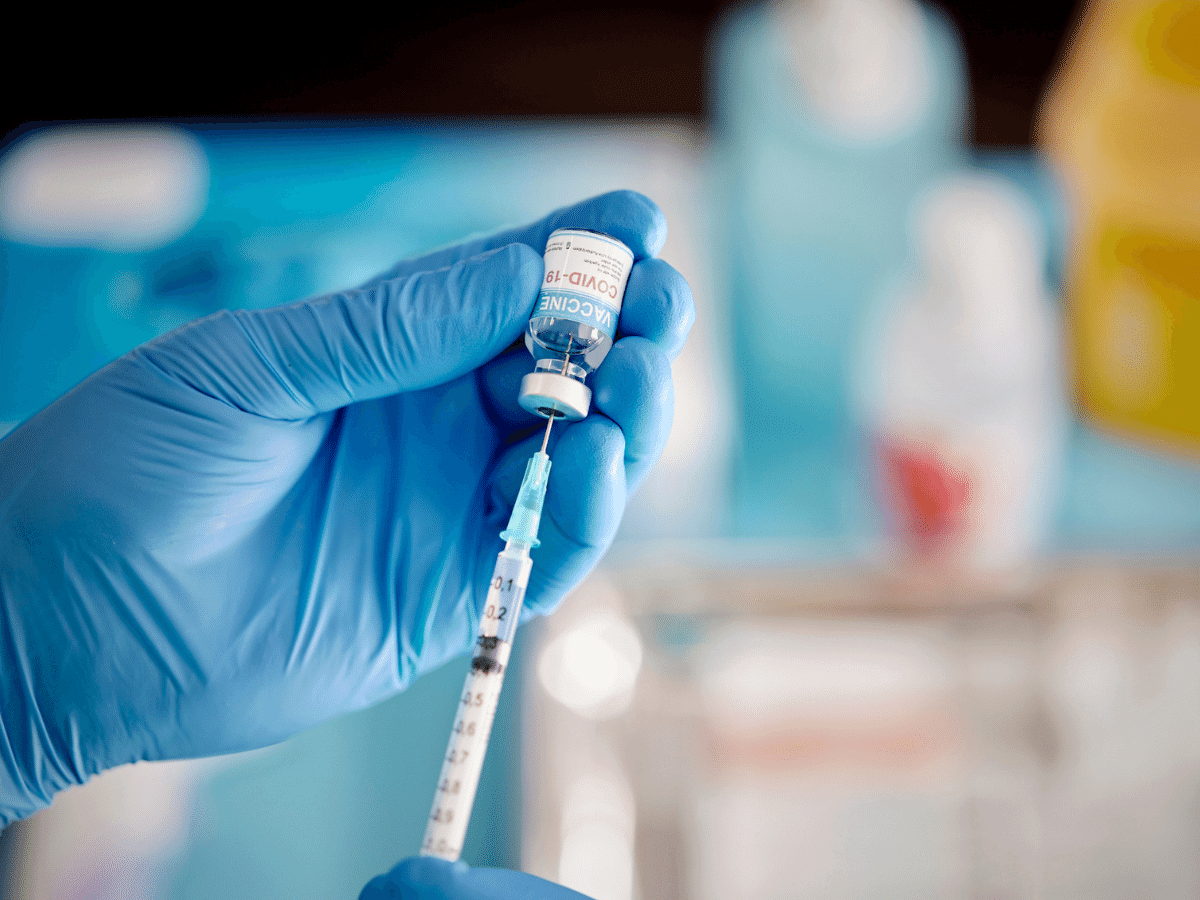 Close up of a gloved hand drawing COVID-19 vaccine into a syringe
