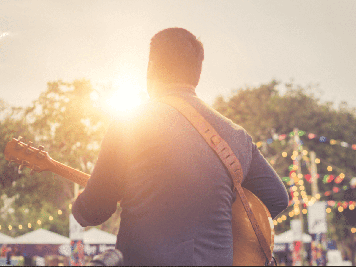 Musician playing guitar on stage at sunset