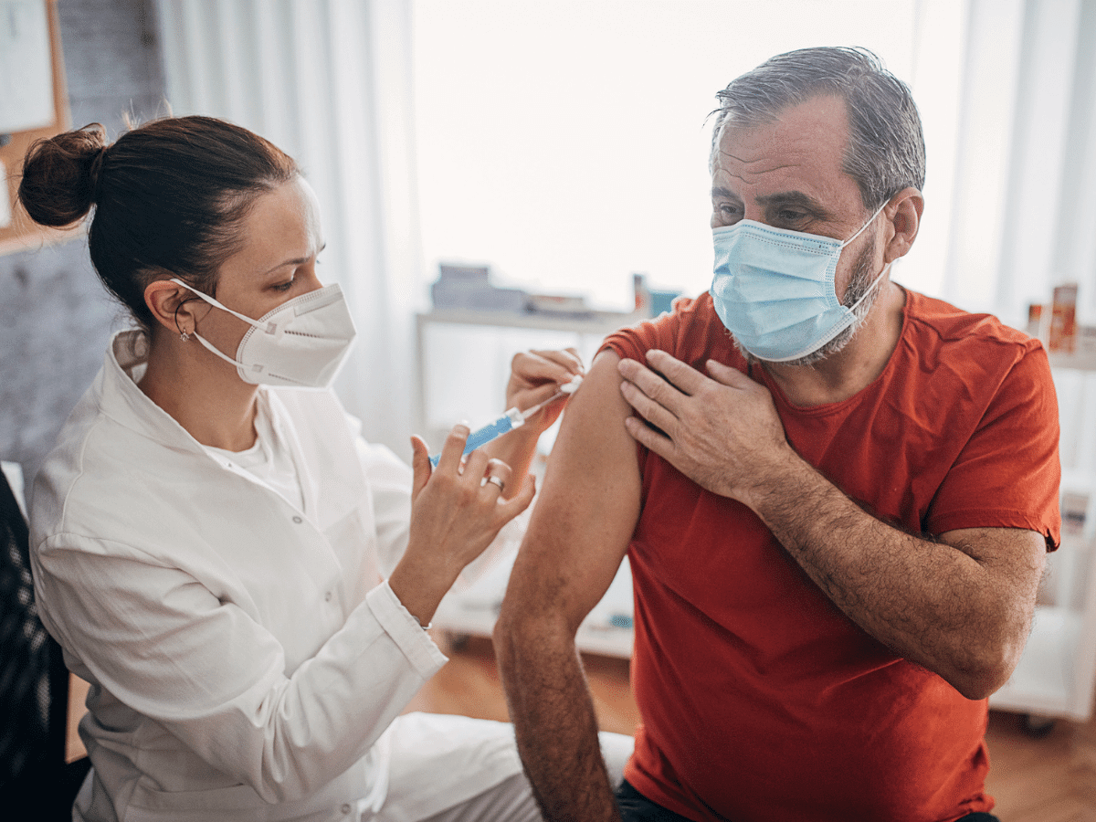 Man receiving a vaccine from a female nurse.