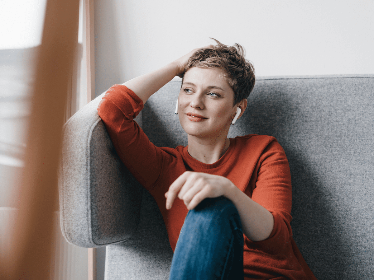 woman sitting on a couch listening to earbuds