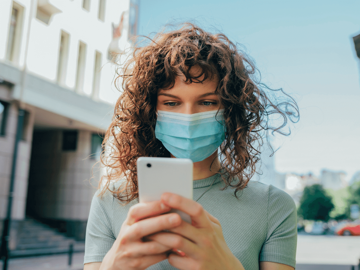 Woman wearing a face mask and reading news on her smartphone