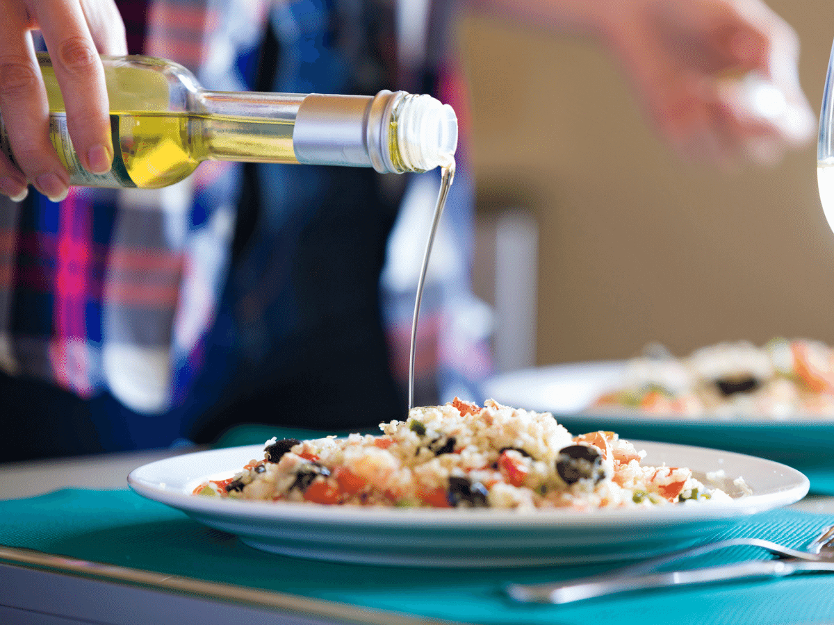 Woman in a home kitchen seasoning a quinoa salad