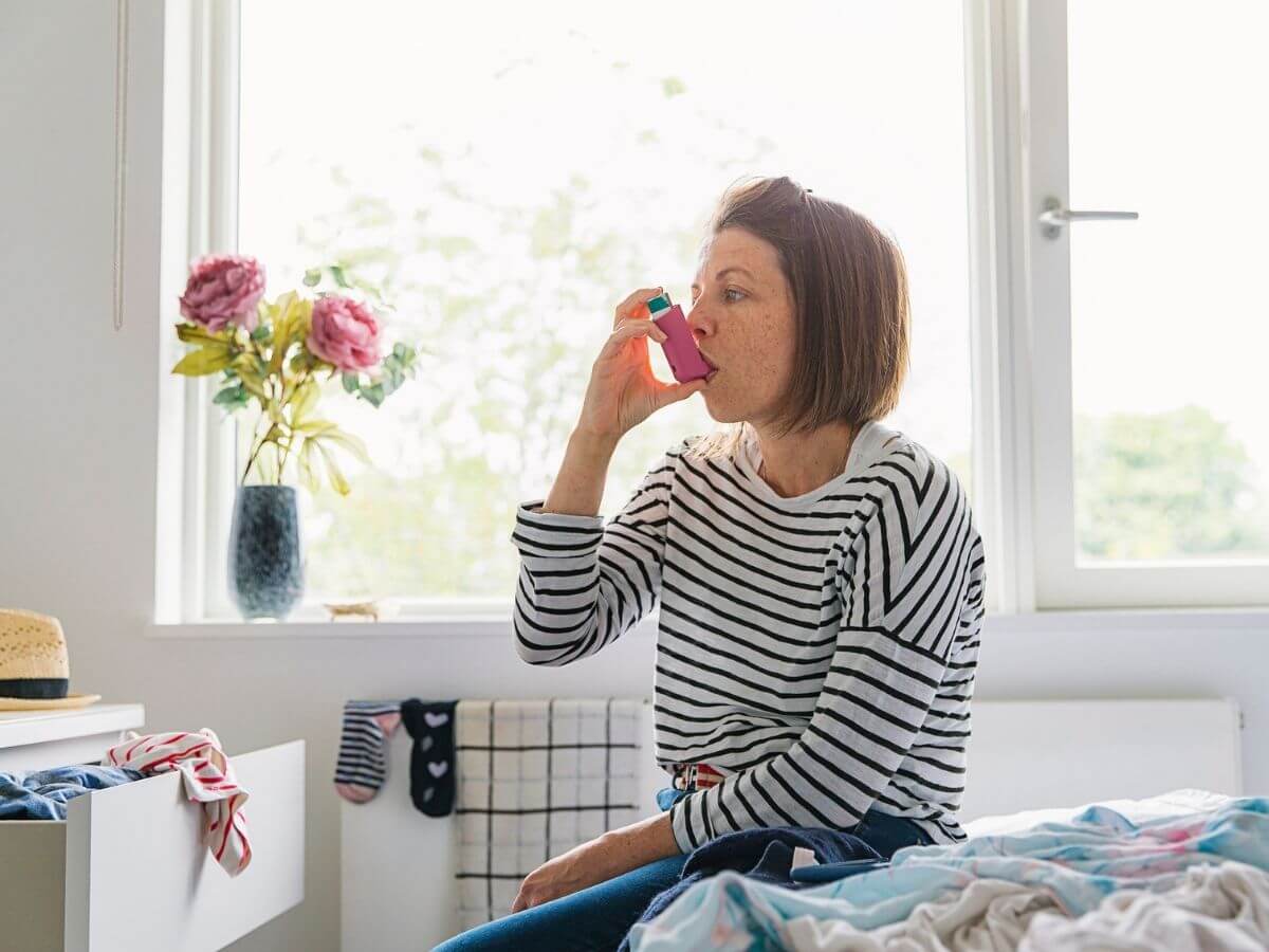 woman using an asthma inhaler at home