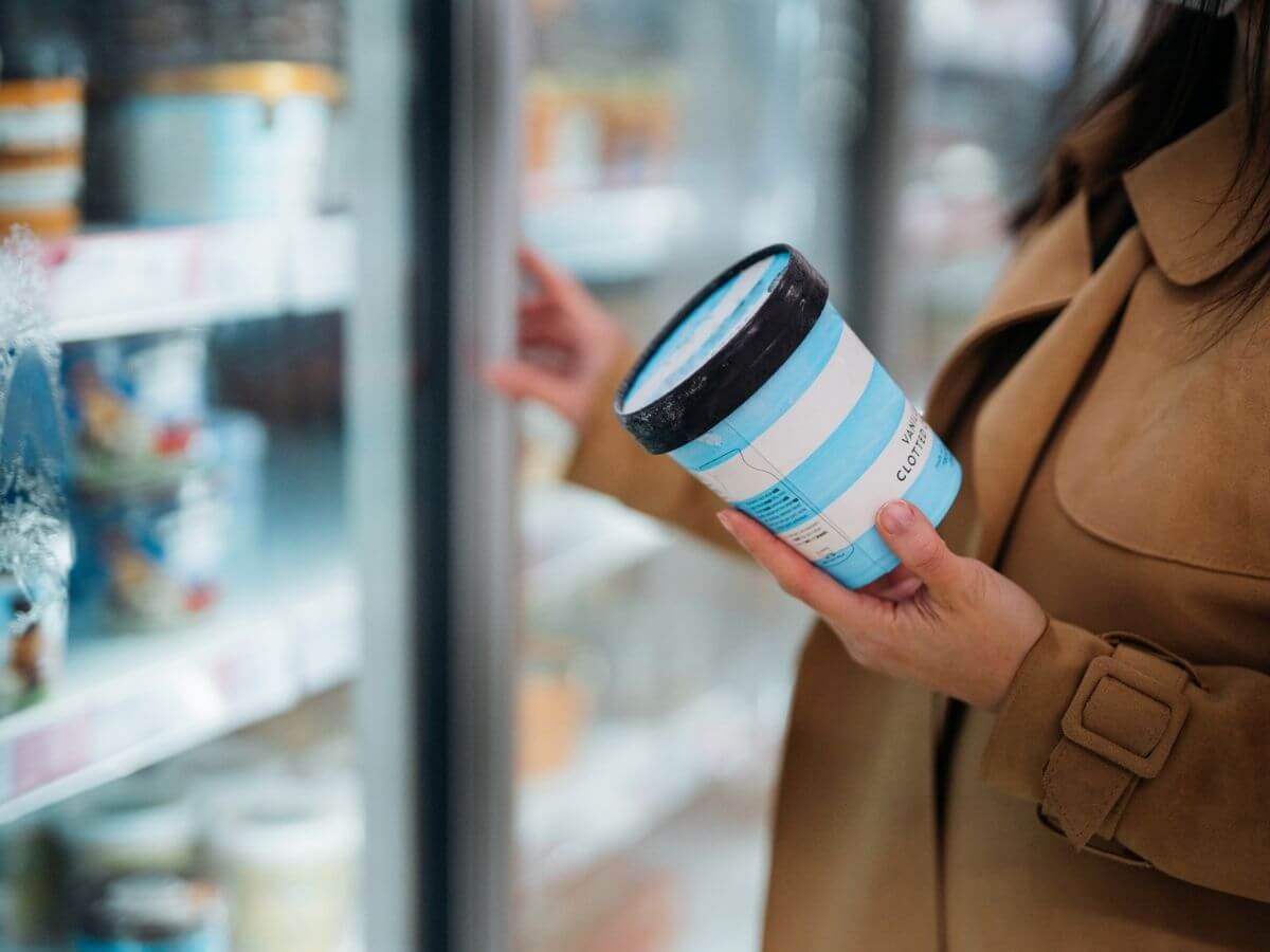 Close up of a woman shopping for ice cream in the frozen section of a grocery store