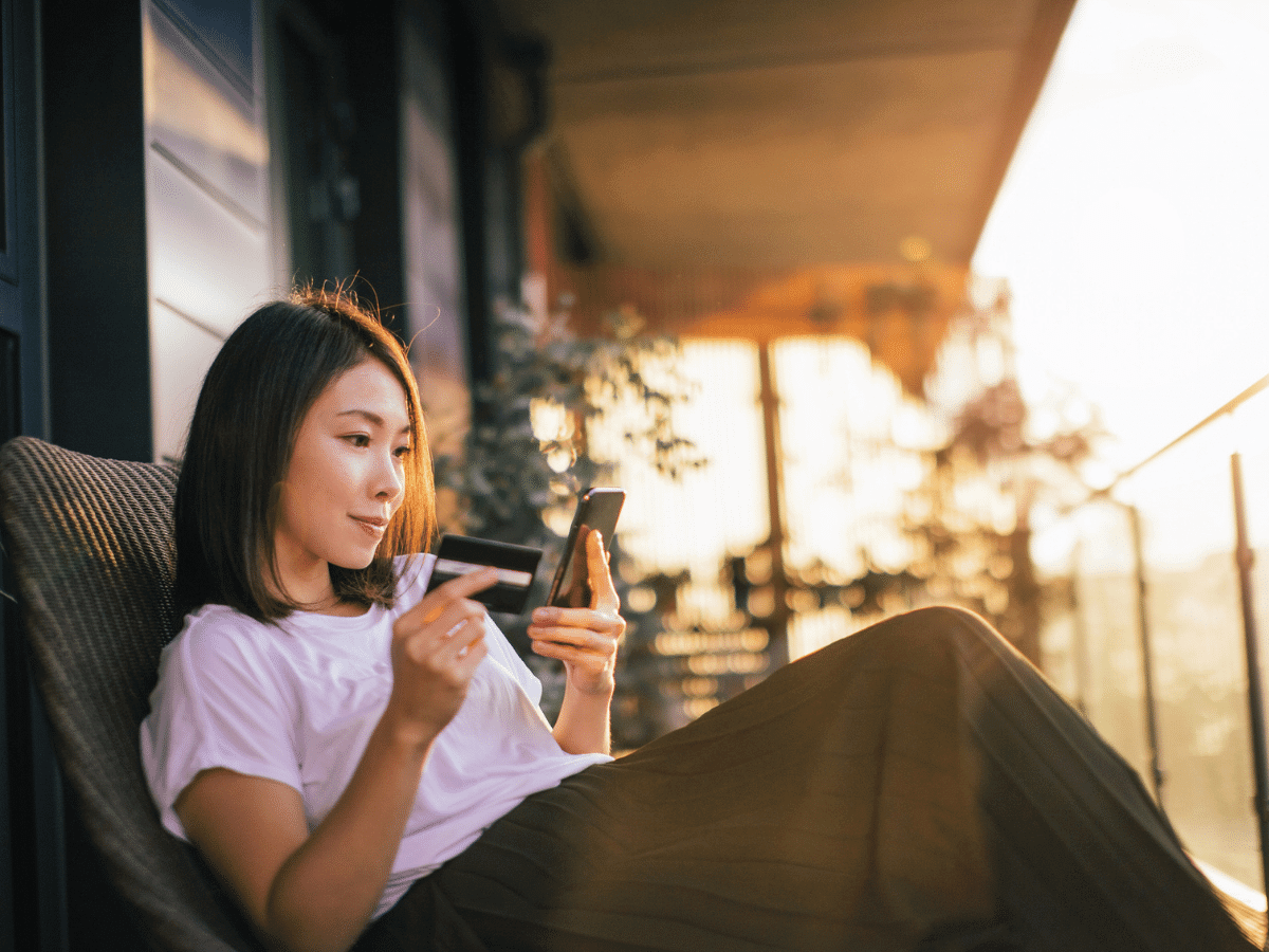 Young woman reading on her smartphone at home while the sun sets.
